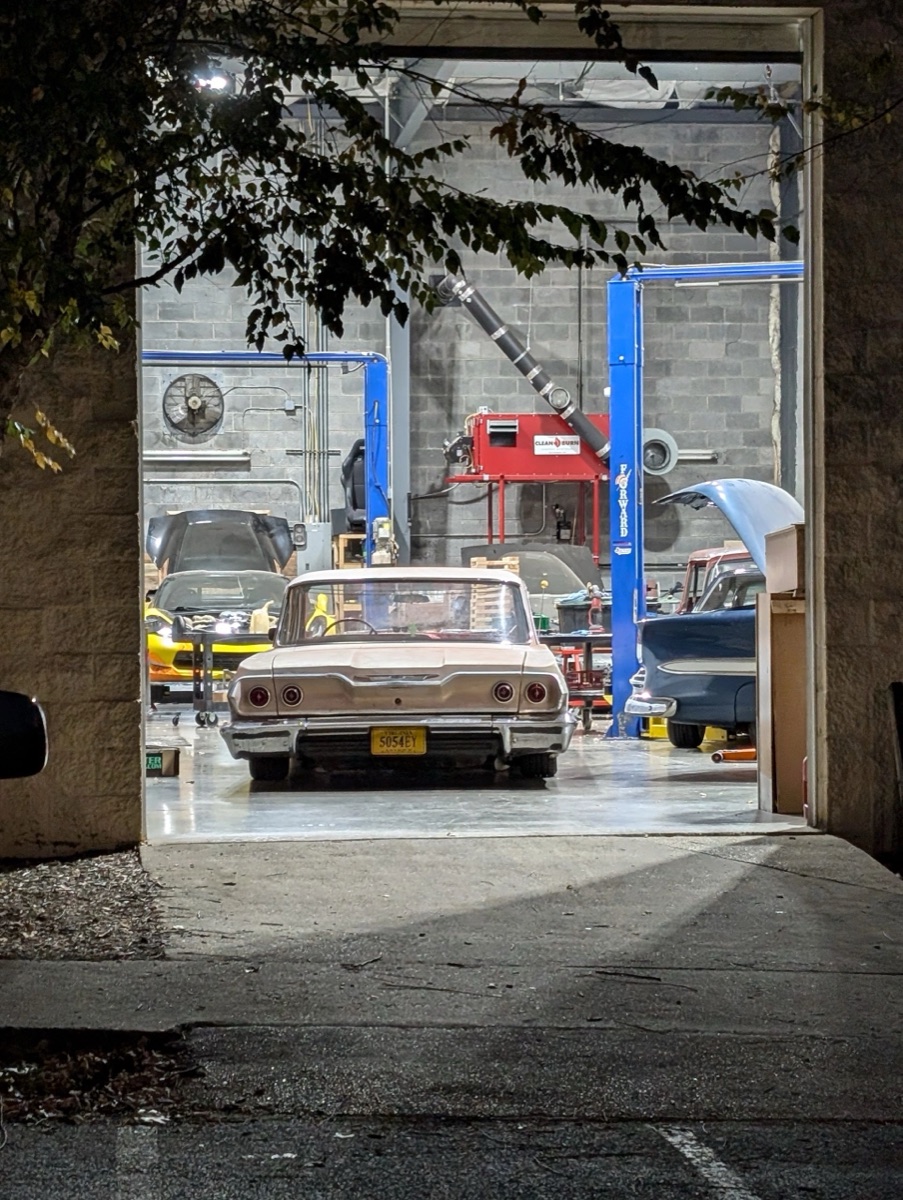 A classic Chevrolet parked inside the lit BuiltWright service bay at night